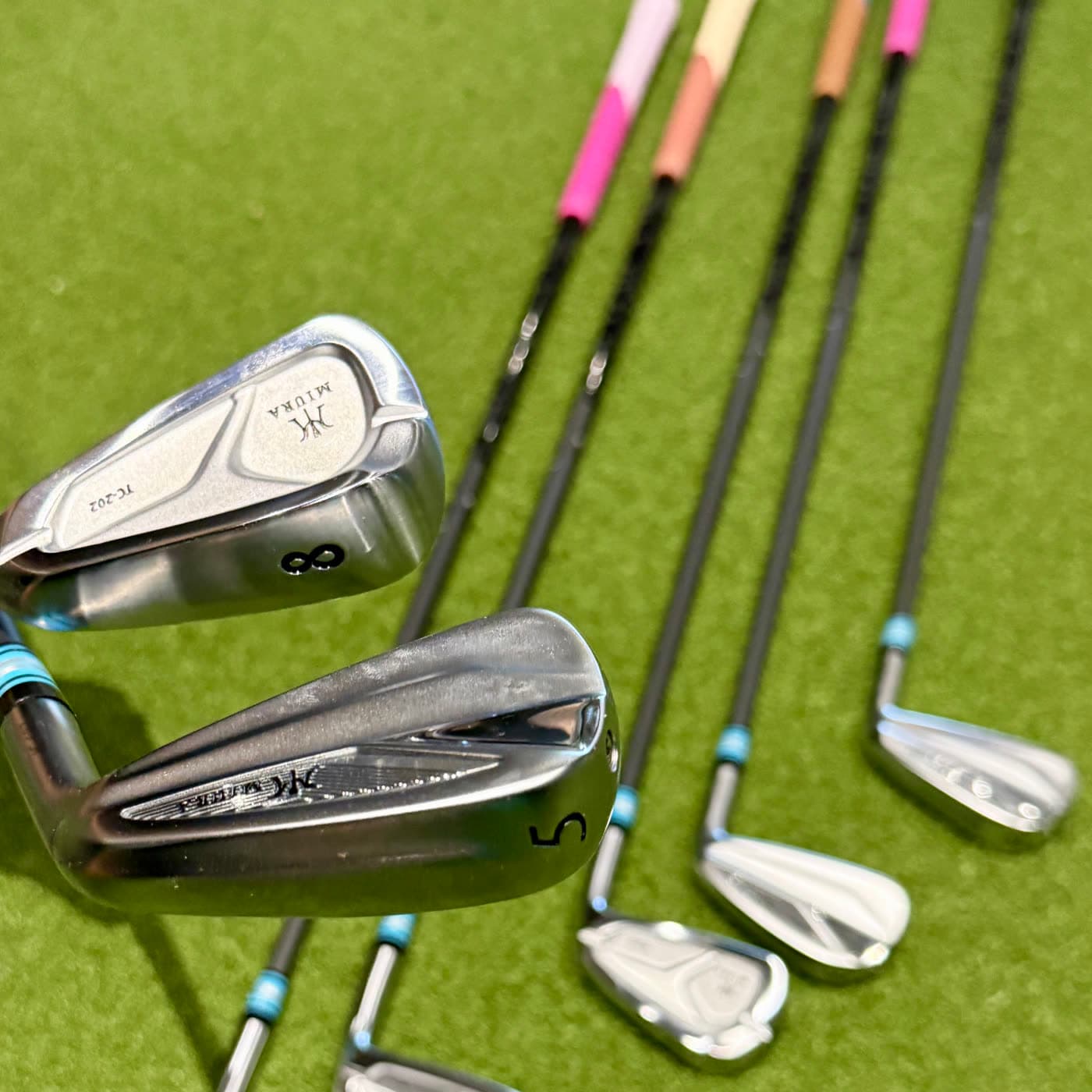 Miura irons built with custom coloured grips, on the putting turf